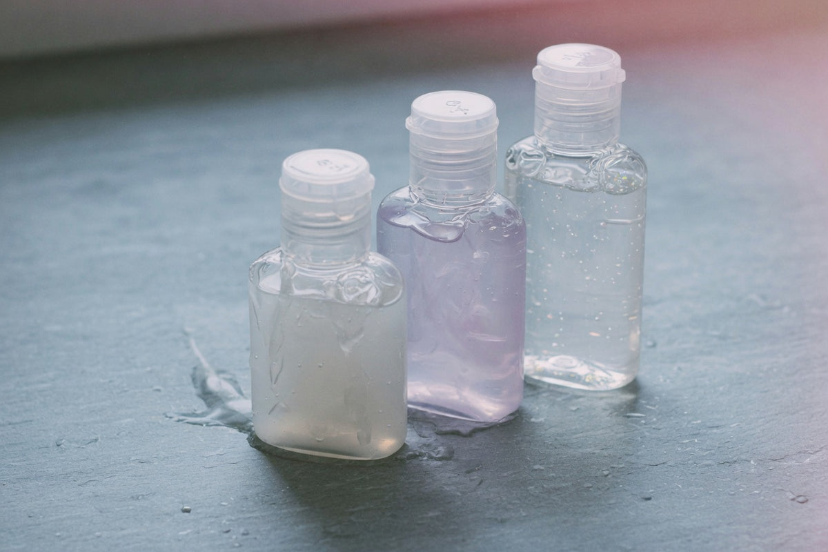 A dark bottle of personal lubricant and a folded black cloth on a low bedside surface — ready for anal play, no product logos