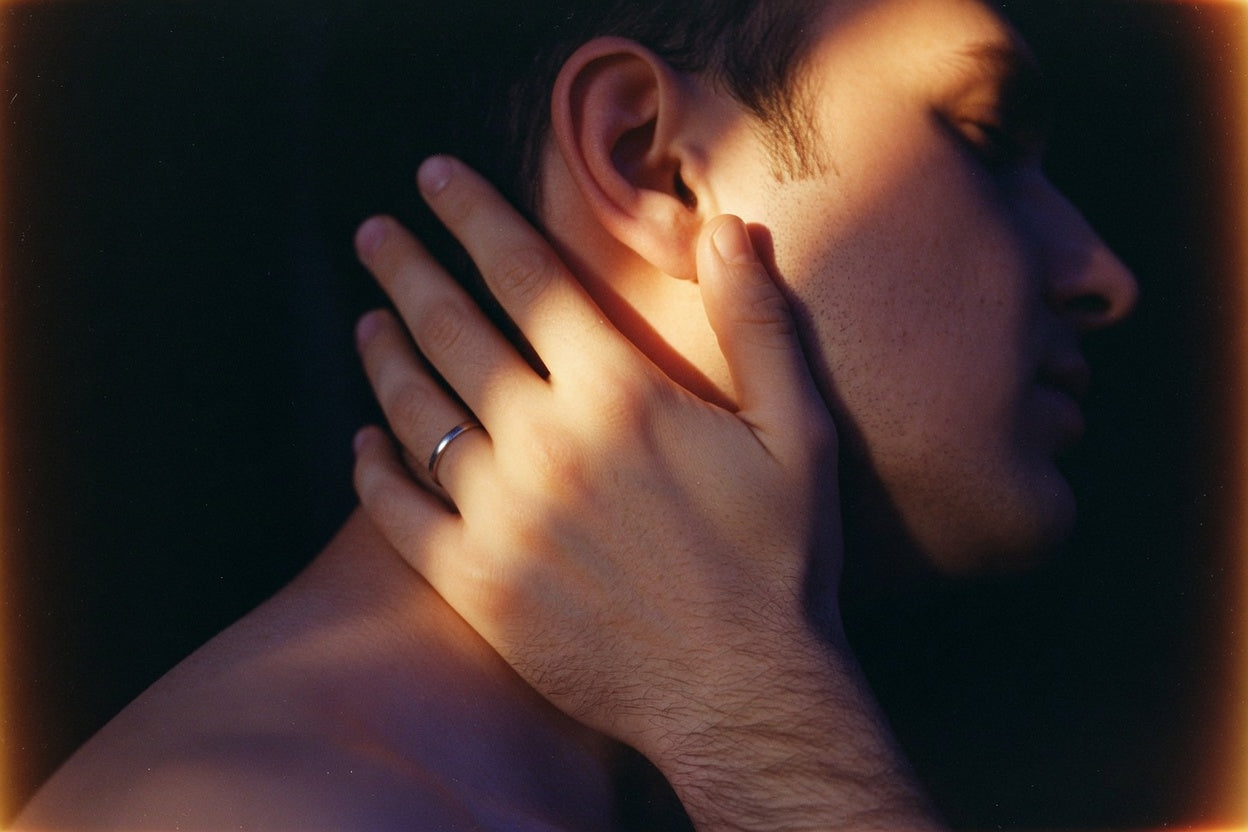 Close film still of an adult mouth near another adult's ear — the private distance where praise kink dirty talk lands