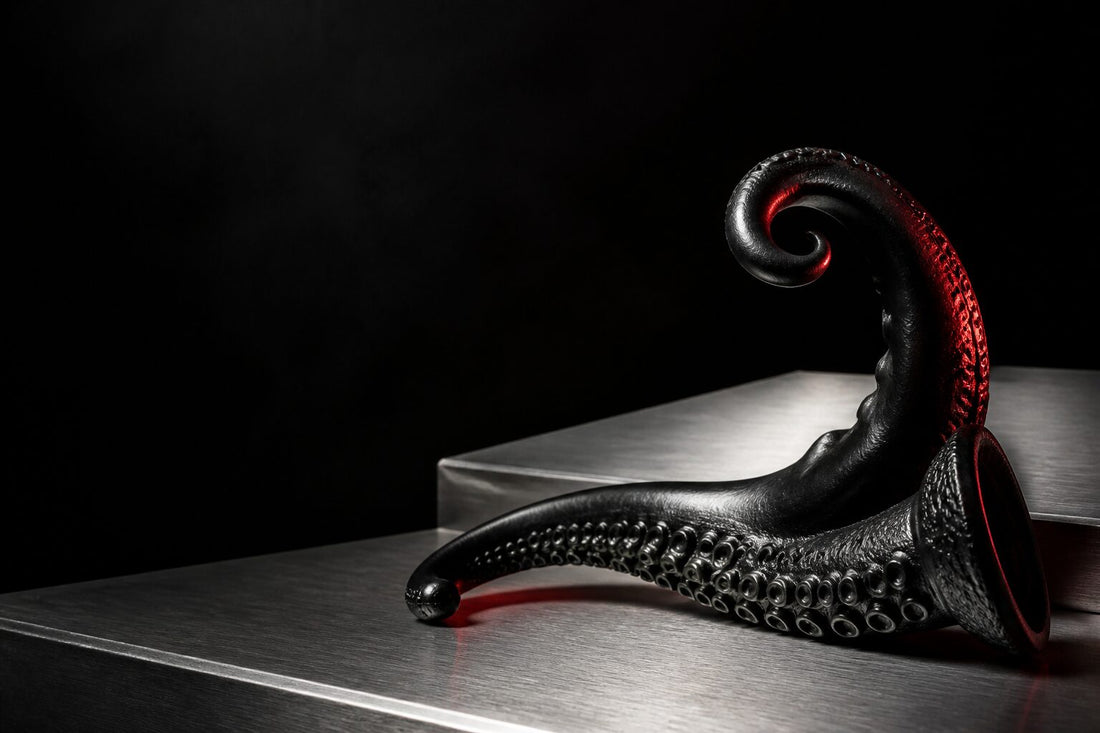 Black silicone tentacle sculpture curling across brushed steel under red club light