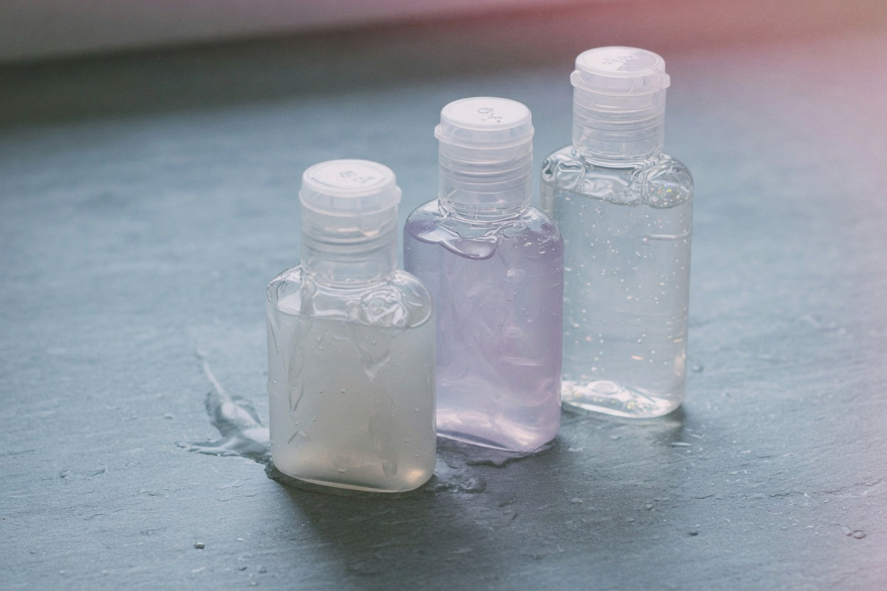 A dark bottle of personal lubricant and a folded black cloth on a low bedside surface — ready for anal play, no product logos